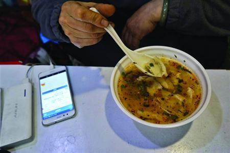 在吃饭时何文妹也不忘盯着手机　本版照片/晨报记者　岳强