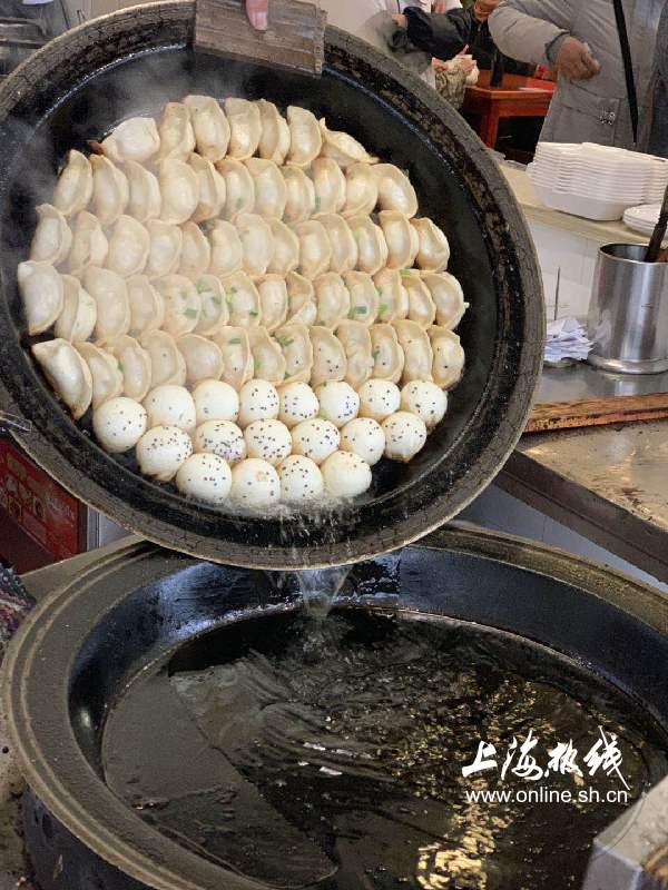 师傅娴熟的翻着锅子,热气腾腾的锅贴生煎在锅中吱吱作响,香气四溢